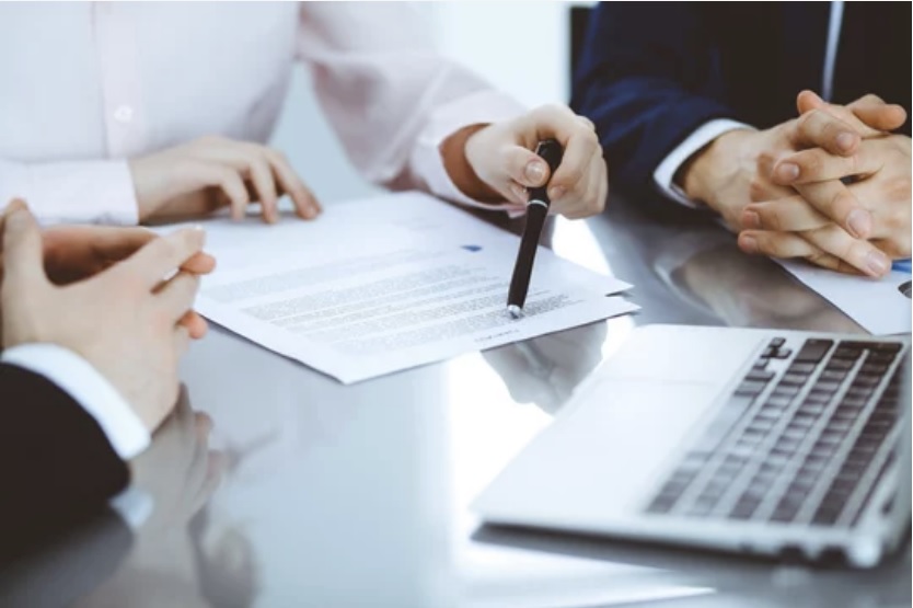 Legal professionals discussing documents with SpineLegal software tools on a laptop for efficient case management.