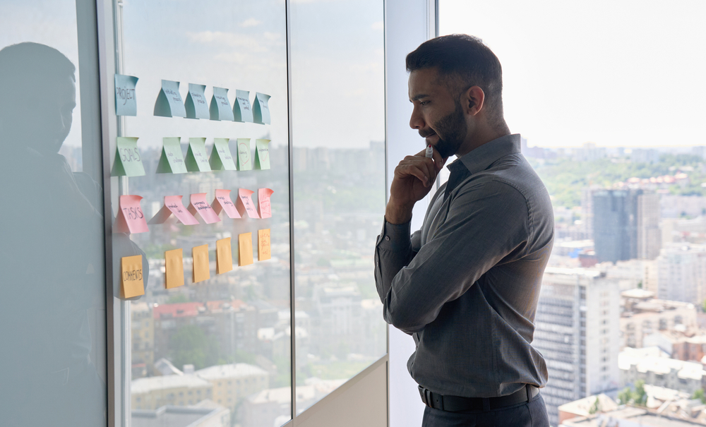 Man planning legal strategies with SpineLegal Software using sticky notes on office window.