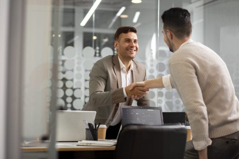 Professionals shaking hands in office, showcasing collaboration with SpineLegal Software solutions.