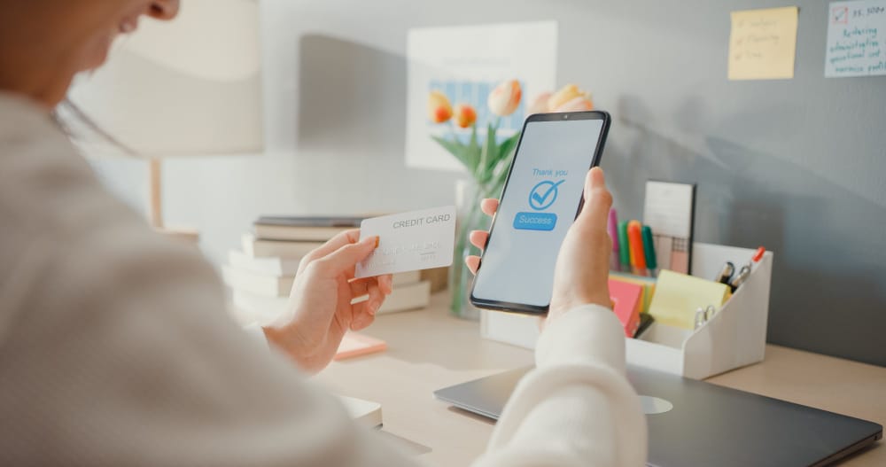Person using SpineLegal Software on mobile, confirming payment with a credit card in a modern office setting.