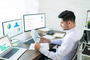 Man analyzing data charts on computer screens using SpineLegal Software for efficient legal case management.