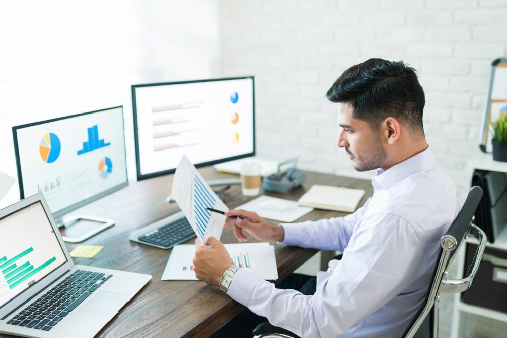 Man analyzing data charts on computer screens using SpineLegal Software for efficient legal case management.